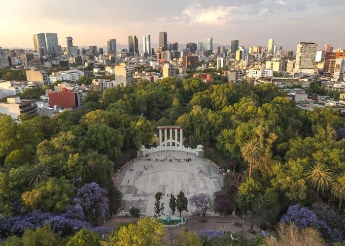 Vista aérea del Parque México en la colonia Condesa con el skyline de Ciudad de México al fondo.