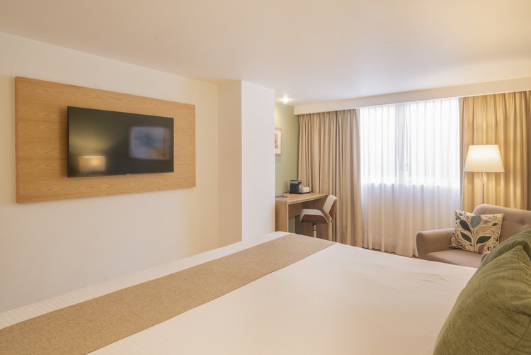 Televisión, escritorio y sillón en Habitación King de Stanza Hotel CDMX