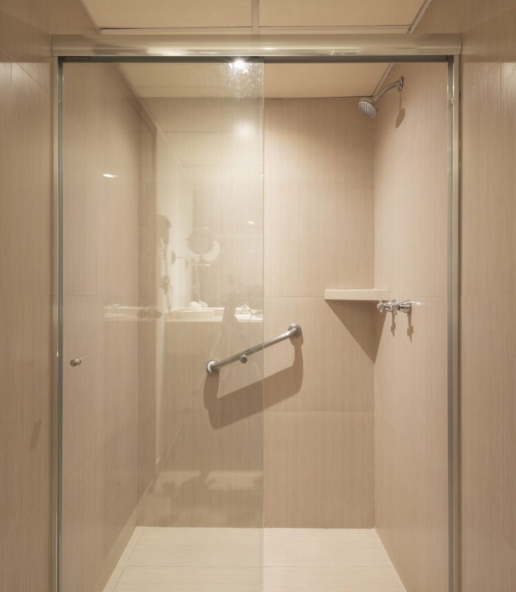 Glass-enclosed shower in the private bathroom of a Single Room at Stanza Hotel CDMX
