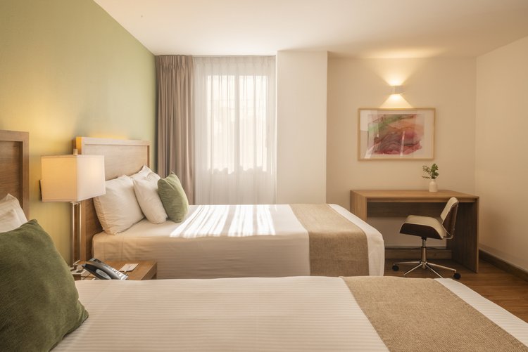 Dos camas matrimoniales y escritorio en Suite Doble de Stanza Hotel CDMX